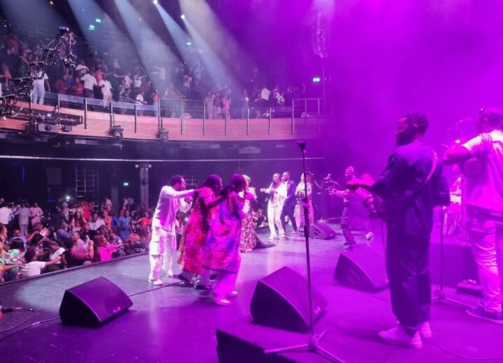 Concert stage with performers, magenta lighting and audience