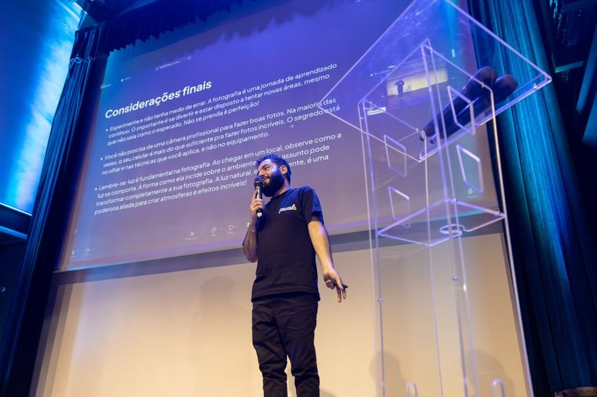 Speaker presenting on a lit conference stage with a large screen