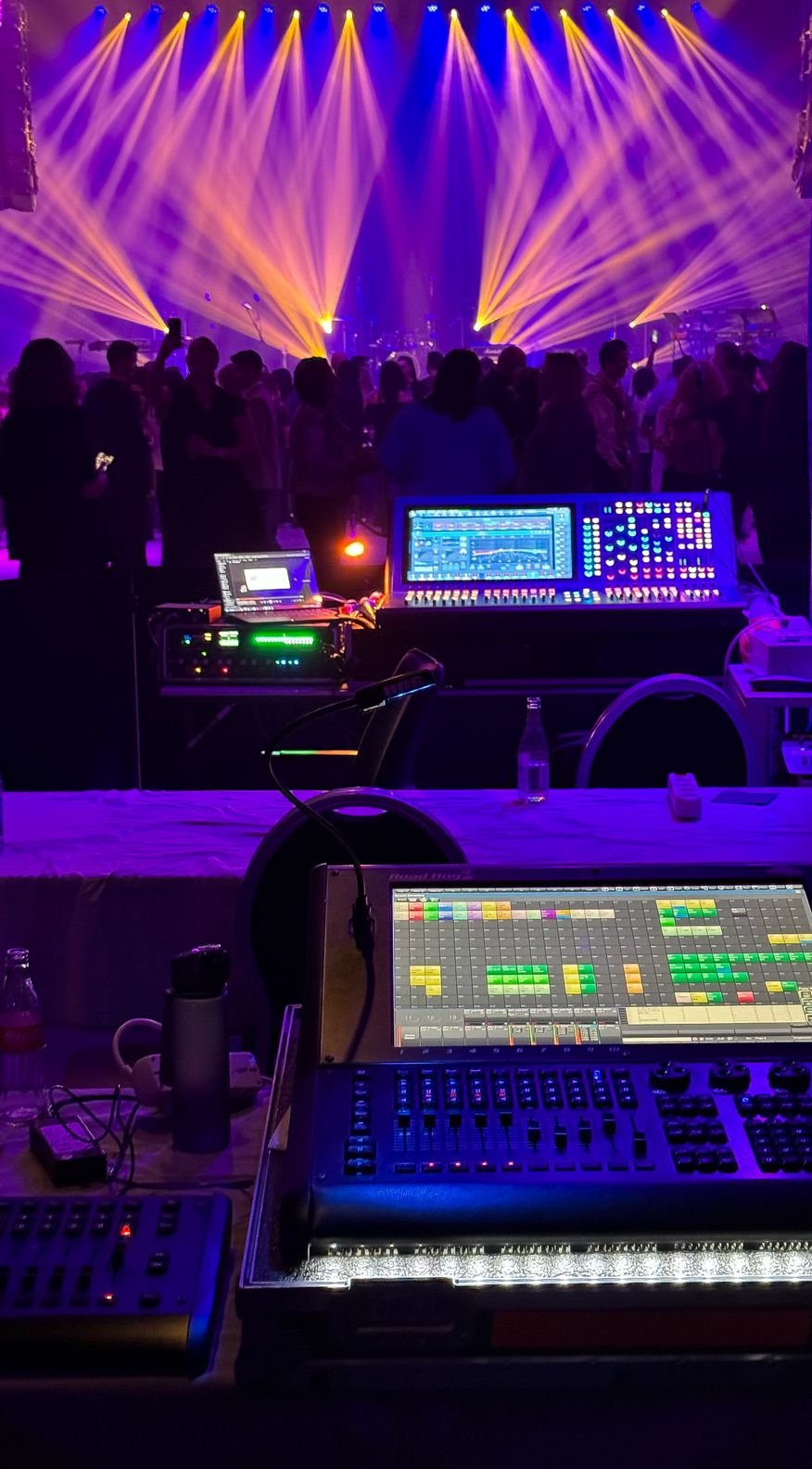 Front of house lighting and sound desks under concert light beams