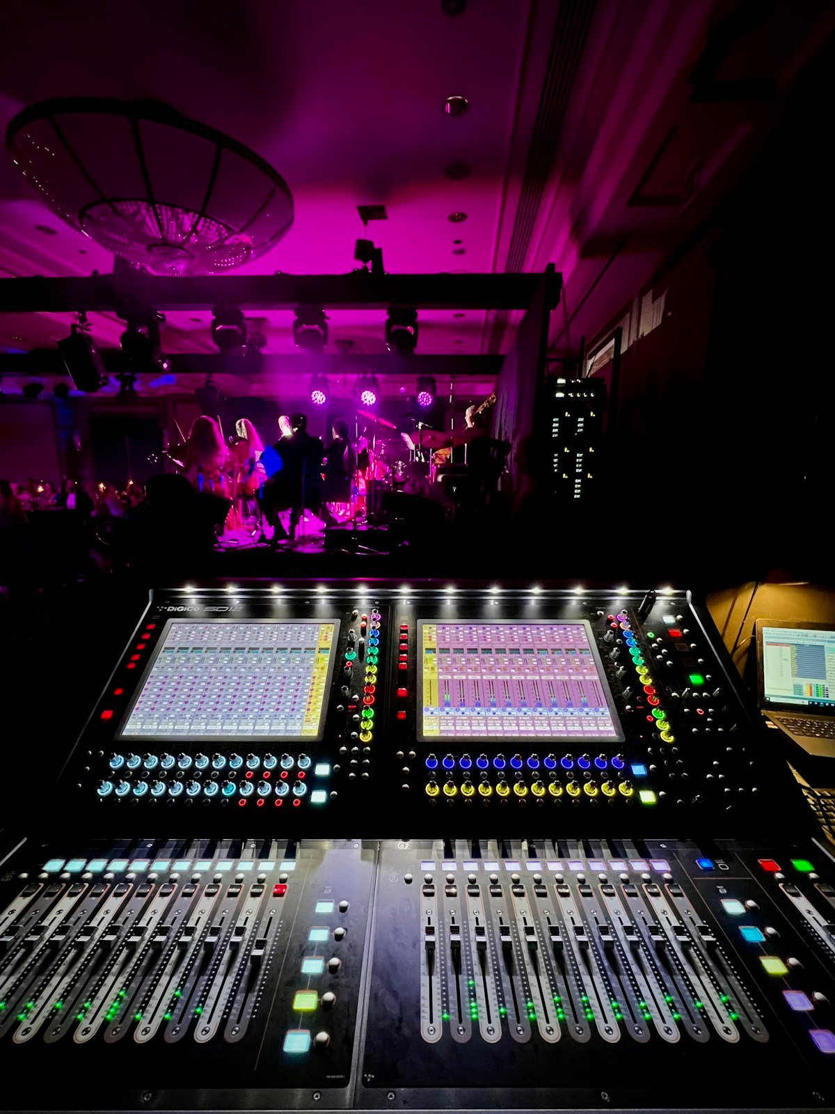 Mixing console at front of house facing a concert stage